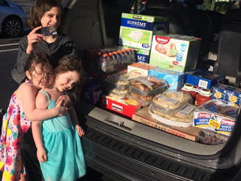 Stephenson Family's three children smile by trunk full of gifts for a family in need. 